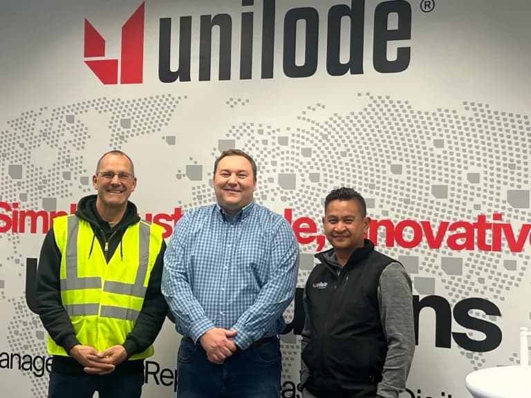 Three members of the Unilode team in front of a branded wall